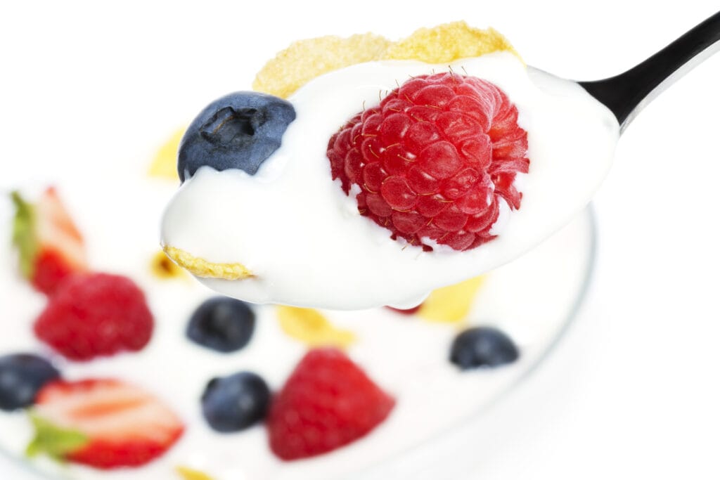 löffel mit himbeere heidelbeere und cornflakes über dessert